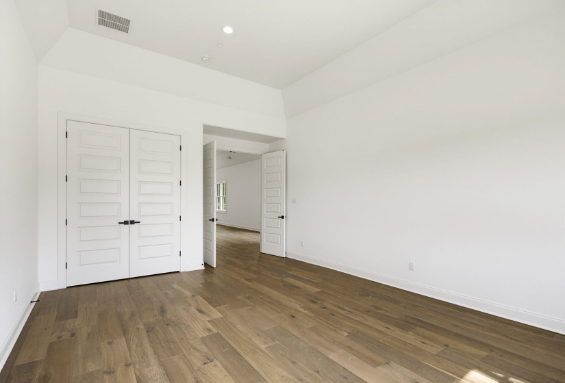 Spacious room featuring wood-finish flooring and pristine white walls