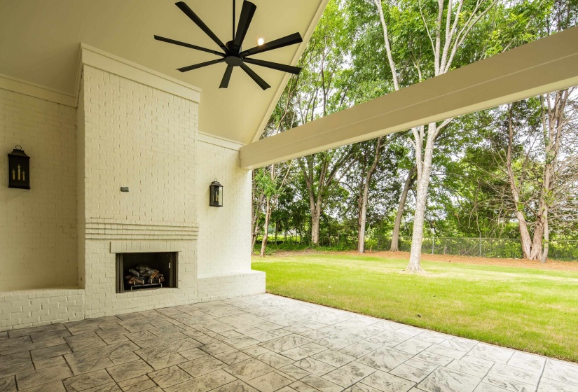 Covered patio with a white brick fireplace and hearth