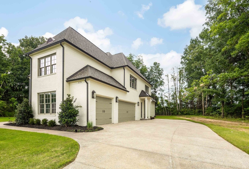 Contemporary residence featuring a light-colored brick exterior with dark trim and a dark shingle roof