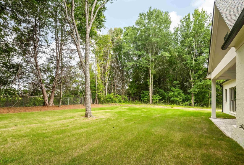 Expansive green lawn framed by mature trees, offering a private outdoor environment