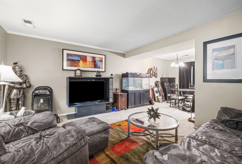 Open-concept living area with neutral wall tones and crown molding
