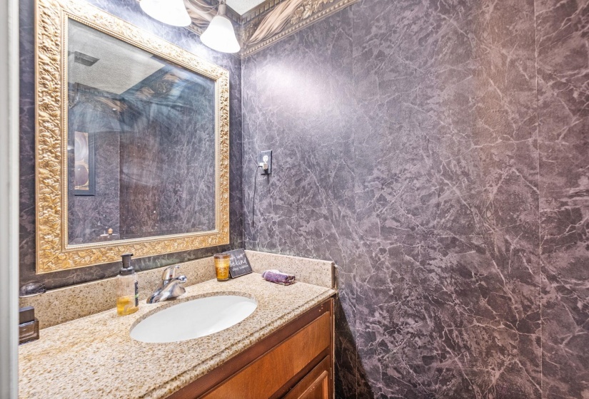 Bathroom vanity featuring a granite countertop, undermount sink, and a framed mirror