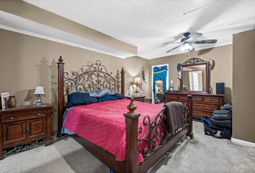 Carpeted bedroom featuring neutral-toned walls, crown molding, and a ceiling fan with integrated lighting