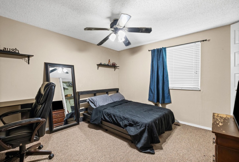 Carpeted room featuring a ceiling fan, a window with horizontal blinds, and a built-in wall shelf