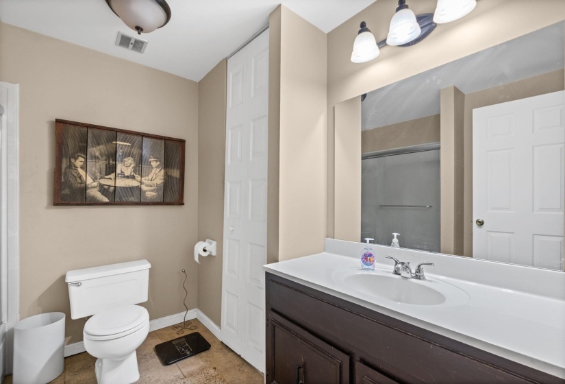 Bathroom featuring a single vanity with a white countertop and dark wood cabinetry, a mirror, and a toilet