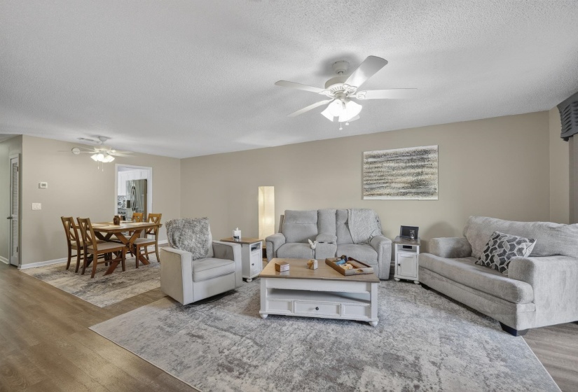 Open-concept living and dining areas featuring wood-finish flooring, neutral wall tones, and ceiling fans for comfort