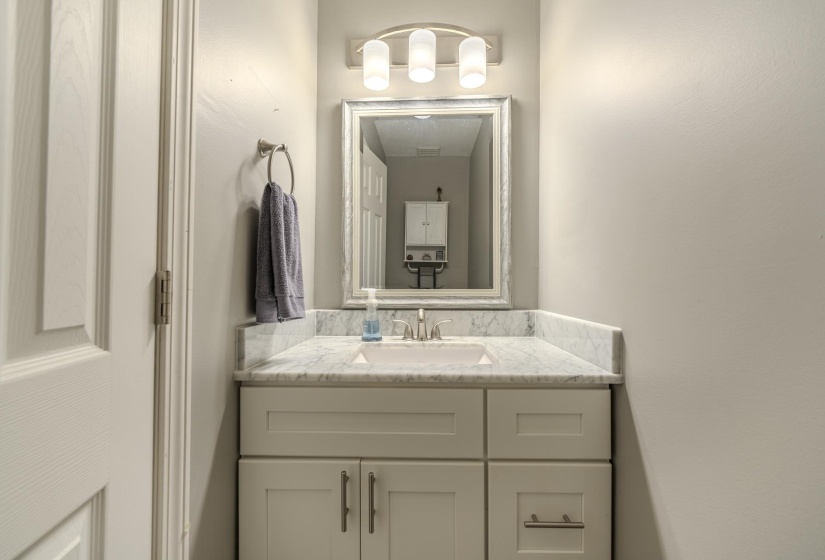 Vanity with a white shaker-style cabinet, integrated sink, and stone-finish countertop