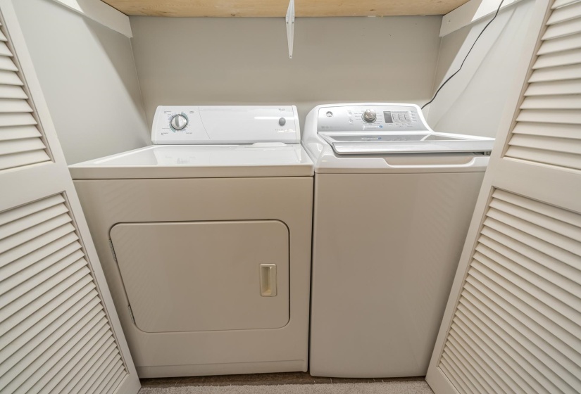 Dedicated laundry area featuring a white top-load washer and a white front-load dryer, enclosed by louvered bifold doors