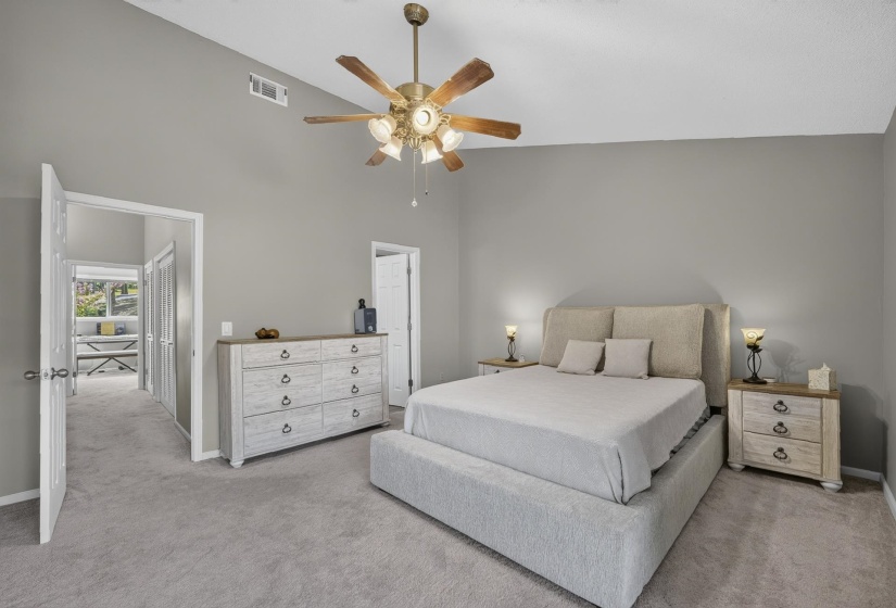 Spacious bedroom featuring vaulted ceilings, a ceiling fan with integrated lighting, and neutral wall tones