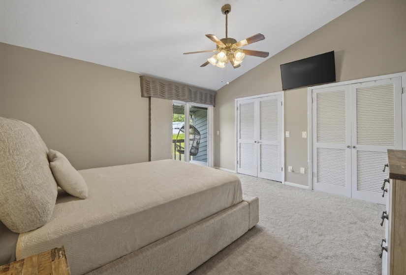 Vaulted ceiling room featuring light-colored carpeting and a ceiling fan with light fixture