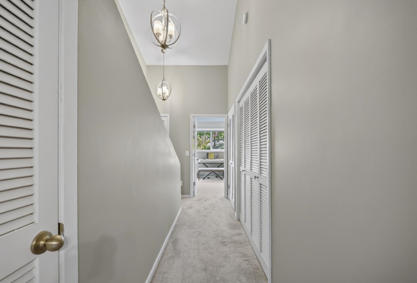 Hallway featuring vaulted ceilings and two spherical pendant light fixtures leading to Bedroom 2