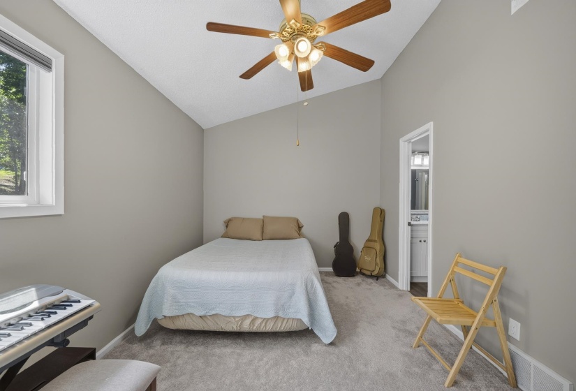 Carpeted room with vaulted ceilings and a ceiling fan