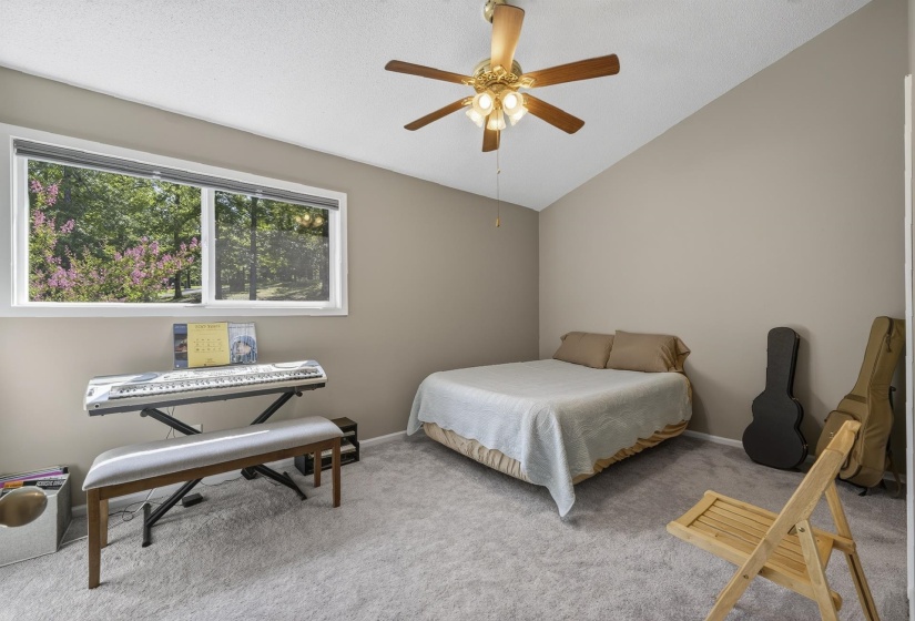 Carpeted room featuring a vaulted ceiling and a ceiling fan with integrated lighting