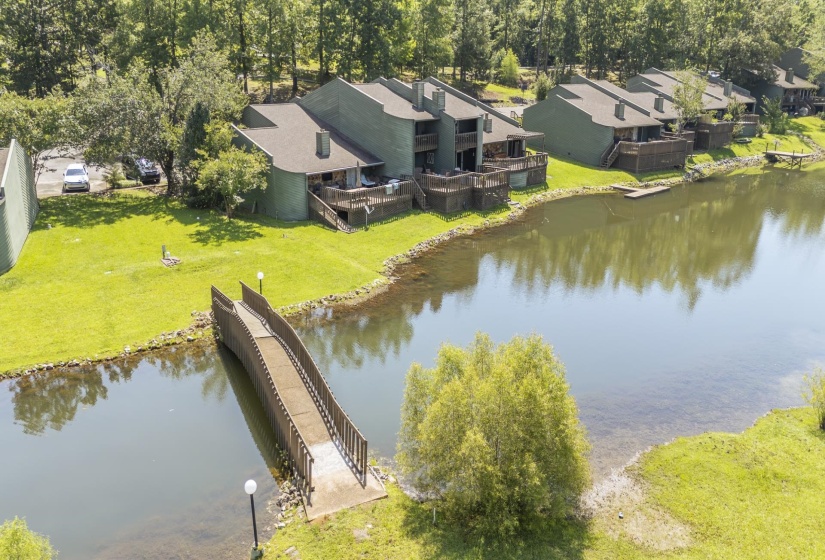 Lakeside multi-story townhomes featuring private decks overlooking the water, individual parking spaces, and a shared pedestrian bridge
