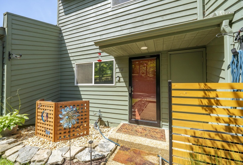 Entryway featuring a black-framed screen door, light green siding, and a slatted wooden privacy fence