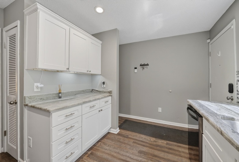 White shaker cabinetry with crown molding, under-cabinet lighting, and light-toned granite countertops