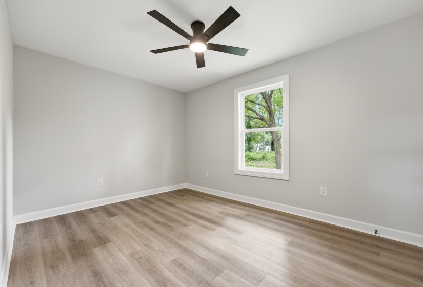 Spacious room with wood-finish flooring, light gray walls, and white trim