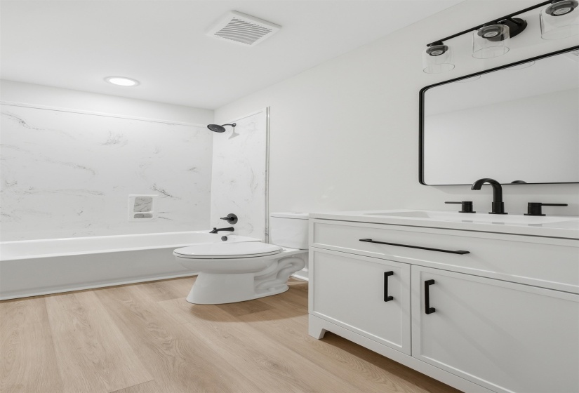 Modern bathroom featuring a white vanity with black hardware, an integrated sink, and a black-framed rectangular mirror