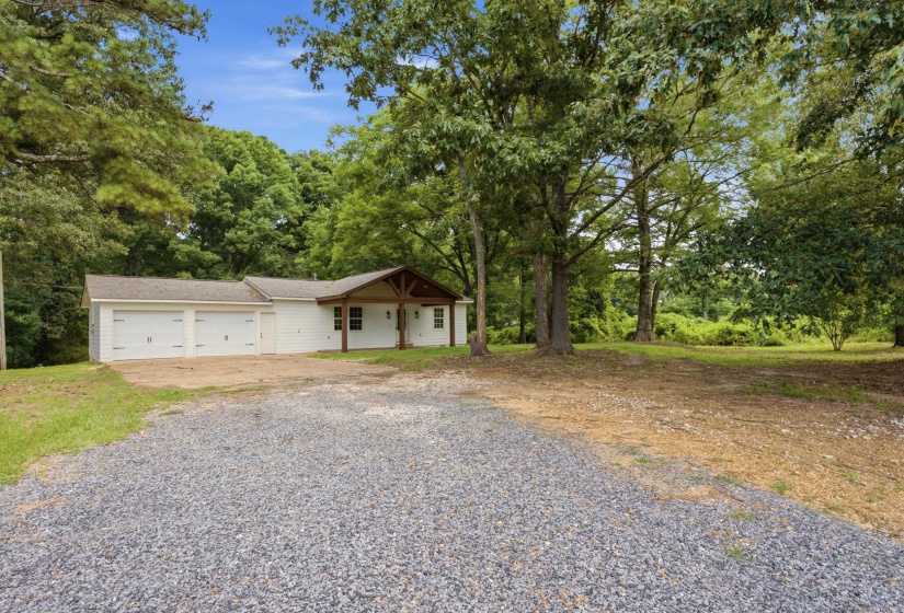 White siding exterior featuring a covered entry porch with exposed wood beams and columns