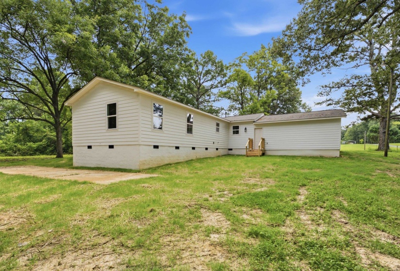 Single-story residence featuring white horizontal siding, a light-colored foundation, and a partial concrete pad