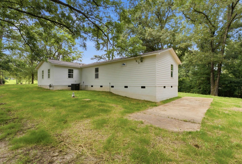 White siding exterior with a pitched roofline, surrounded by mature trees