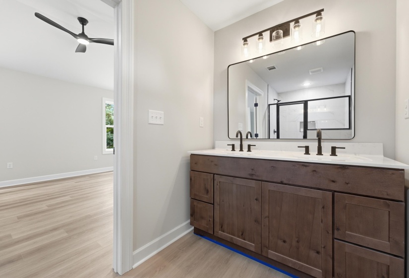 Dual sink vanity with dark wood-finish cabinetry, light-toned countertop, and rectangular mirror with dark trim