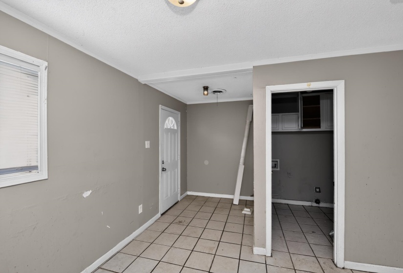 Interior space featuring a white paneled entry door, light-toned tile flooring, and a window with blinds