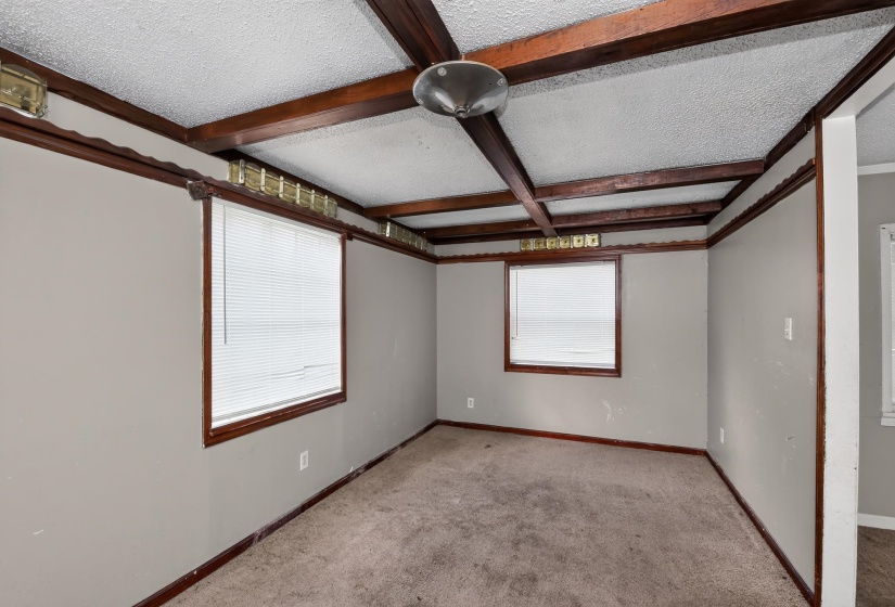Room featuring exposed ceiling beams, two windows with blinds, wall-mounted lighting accents, and a ceiling light fixture