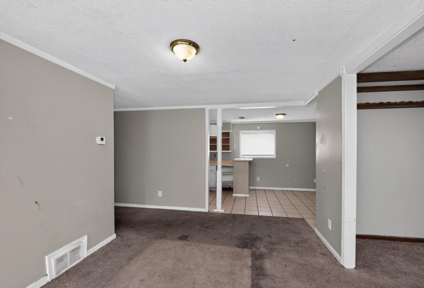 Open concept living space featuring neutral gray wall paint and textured carpet flooring