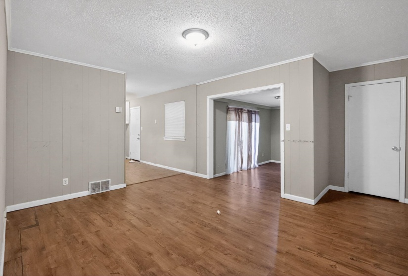Spacious interior featuring wood-finish flooring, light grey paneled walls, white trim, and a semi-flush ceiling light fixture