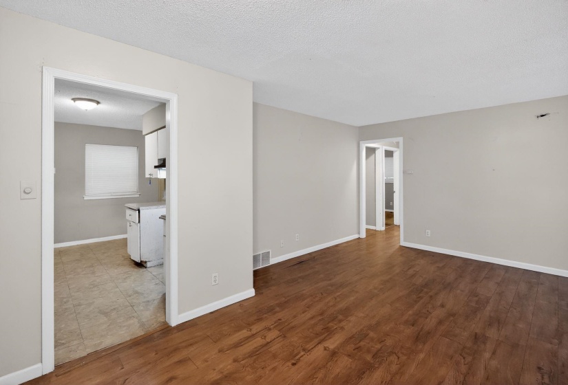 Spacious room featuring wood-finish flooring, light neutral wall paint, and white baseboards