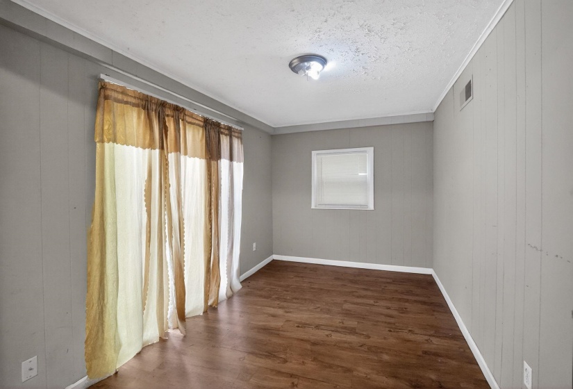 Interior room featuring wood-finish flooring, light gray vertical paneling, and a white framed window