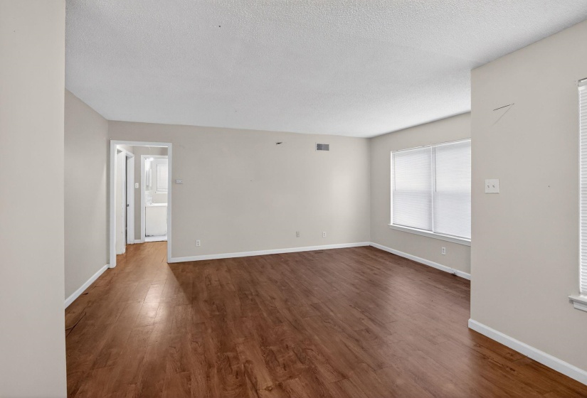 Spacious interior featuring wood-finish flooring, neutral paint tones, and window blinds