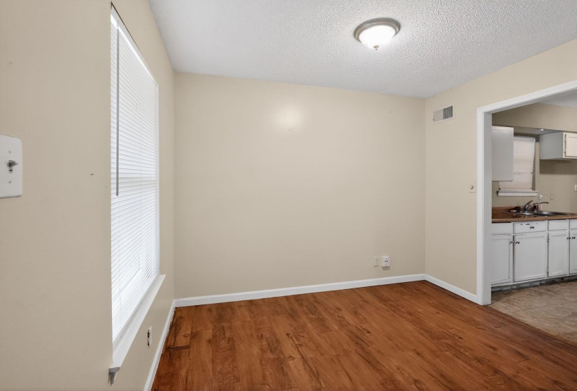 Interior space featuring wood-finish flooring, neutral wall paint, and a window with blinds