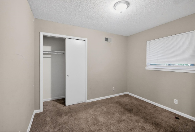 Neutral-toned room featuring brown carpet flooring and a window with blinds