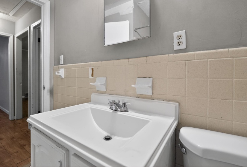 White vanity with an integrated sink, polished chrome faucet, and tiled wainscoting