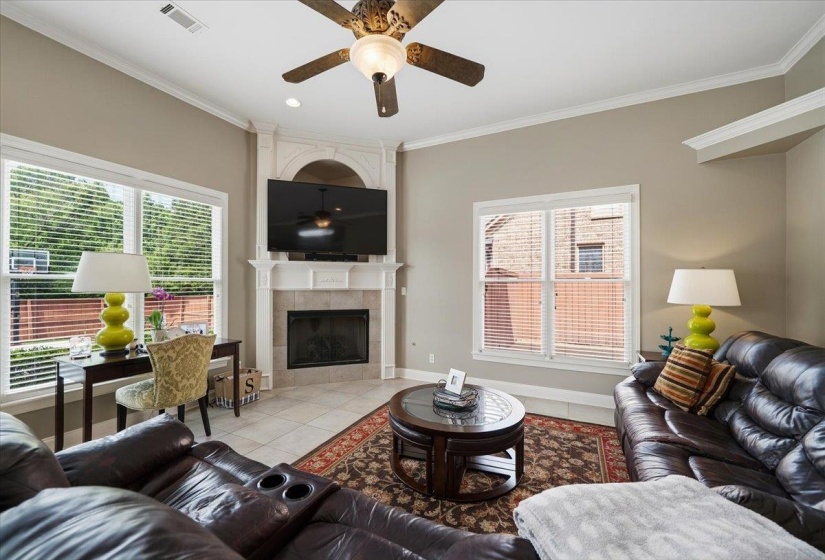 Living area featuring a corner fireplace with a tiled surround, a decorative mantel, and crown molding