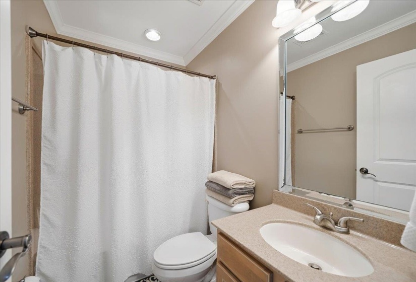 Bathroom featuring a single vanity with a stone-finish countertop, under-mount sink, and framed mirror