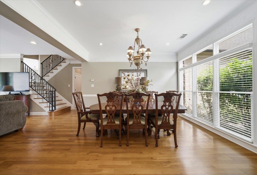 Dining area featuring wood-finish flooring, a decorative chandelier, recessed lighting, expansive windows with blinds, and crown molding