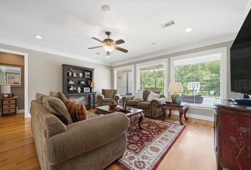 Living area featuring light wood-finish flooring, white crown molding, and recessed lighting