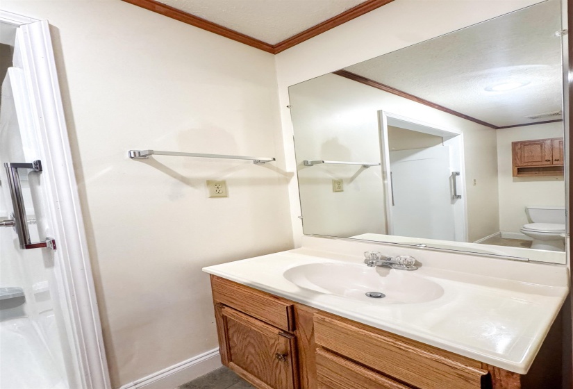 Bathroom vanity with wood-finish cabinetry, integrated sink, and chrome fixtures.