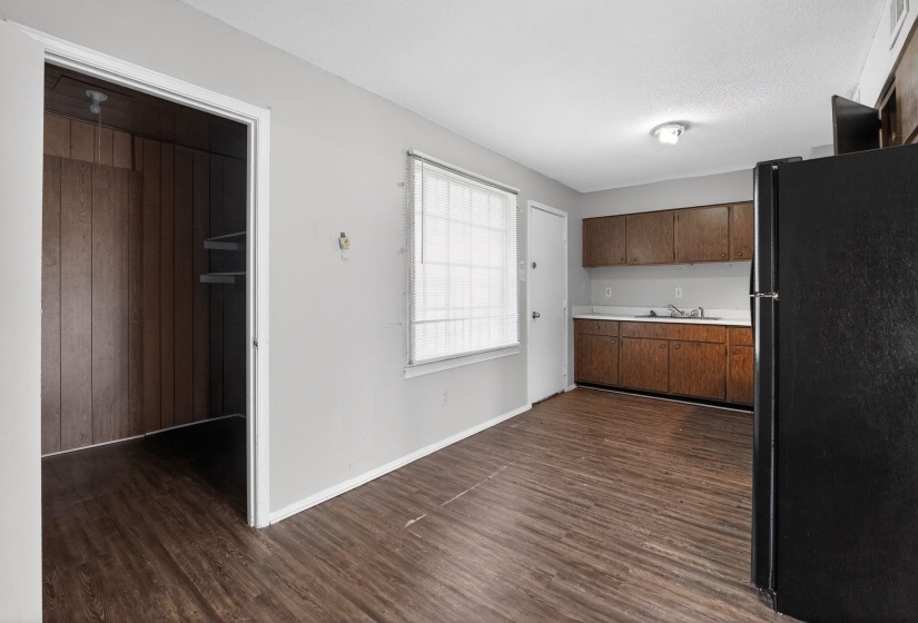 Kitchen featuring freestanding refrigerator, light countertops, dark wood finished floors, and dark brown cabinets