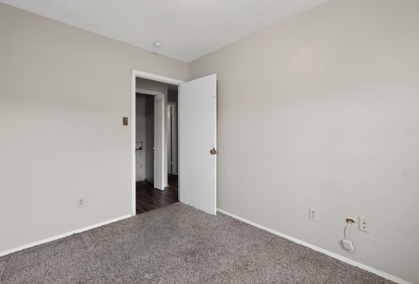 Carpeted empty room featuring a textured ceiling and baseboards