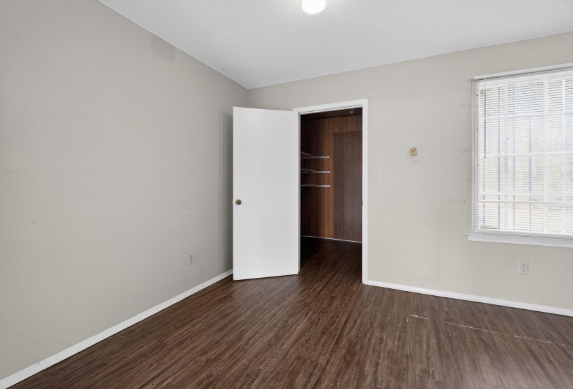 Unfurnished bedroom with a spacious closet and dark wood-type flooring