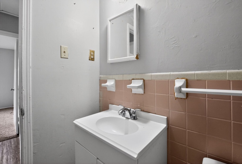 Half bathroom with vanity, a wainscoted wall, tile walls, and a textured wall