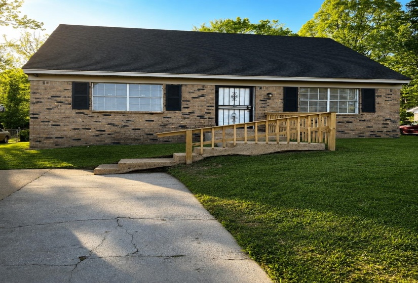 Brick facade residence with a dark shingle roof and a concrete driveway