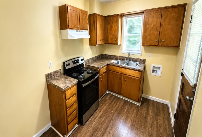 Kitchen featuring wood-finish flooring, wood cabinetry, laminate countertops, and a stainless steel electric range