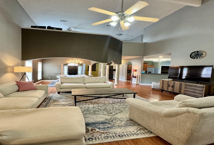 Spacious living area featuring high vaulted ceilings, multiple ceiling fans, and rich wood-finish flooring