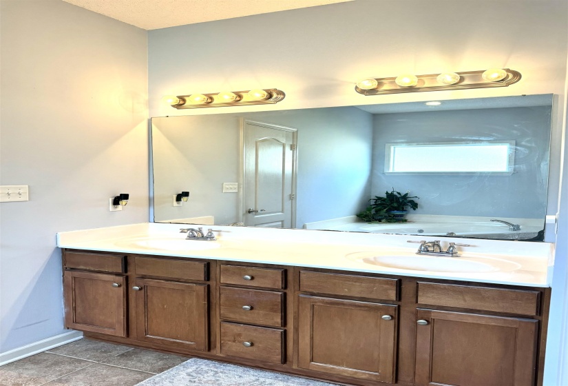 Dual vanity with wood-finish cabinetry, integrated sinks, and polished chrome hardware