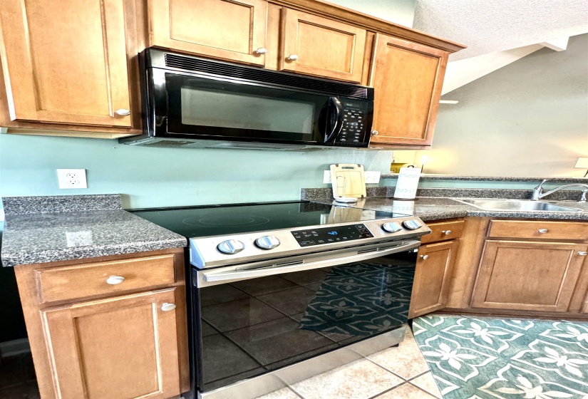 Kitchen featuring a stainless steel range with a smooth cooktop and coordinated microwave